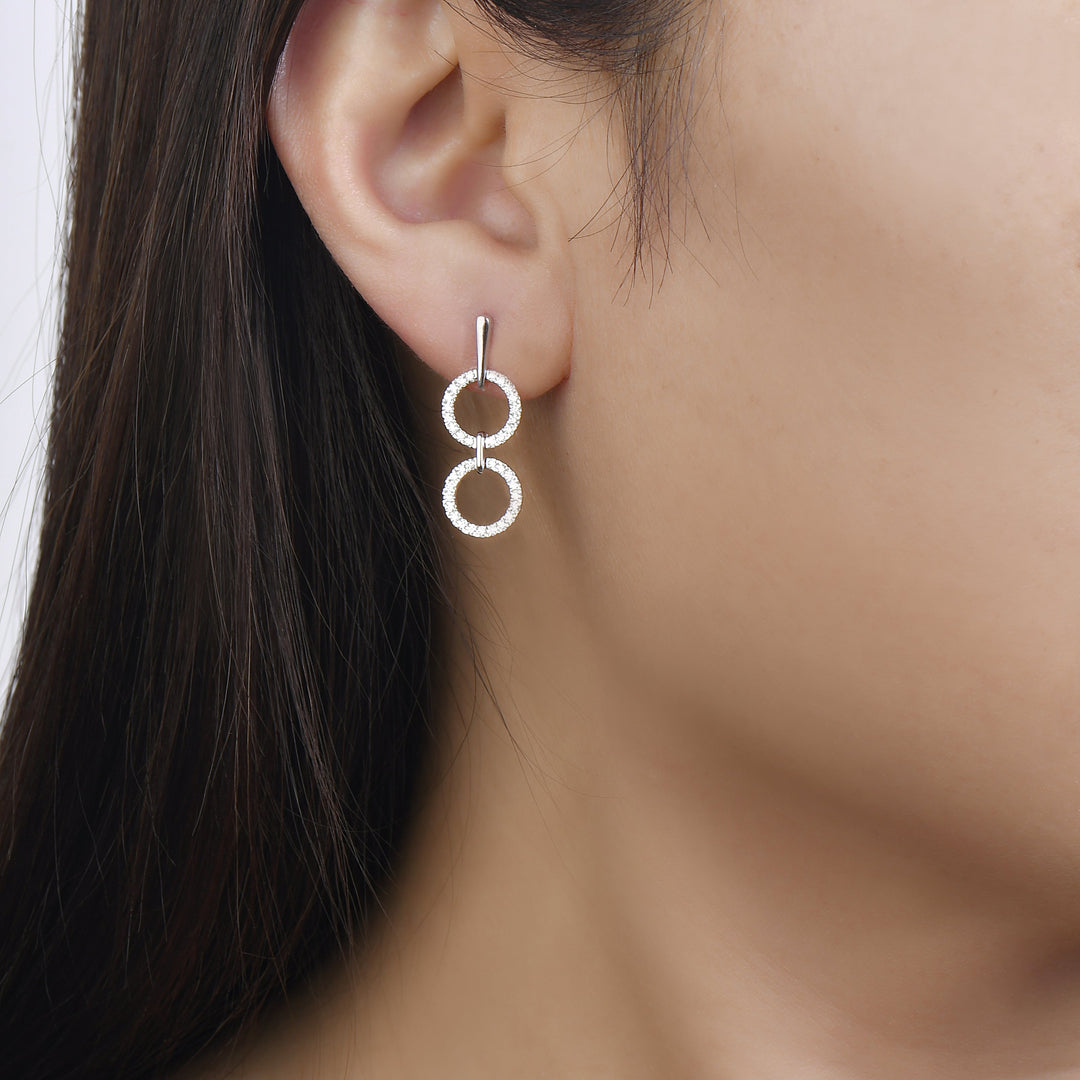 white gold dangling diamond earrings with two open circles connected by a metal bar on model. Unique jewelry, unique earrings. gladiator style earrings. on model