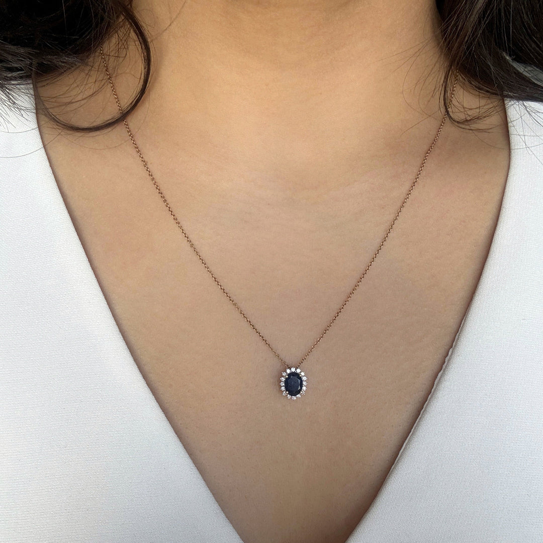 oval shaped blue sapphire pendant with diamond halo in 14k yellow gold 