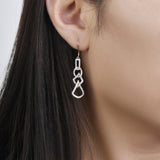 unique jewelry, unique earrings, fashion jewelry, fashion earrings, diamond earrings in rose gold, dangling earrings, dangling diamond earrings, drop earrings, diamond drop earrings, dangling drop earring with a design of geometric shapes intertwined with each other. Earrings have a fishhook back. Earrings on model.