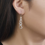 Load image into Gallery viewer, unique jewelry, unique earrings, fashion jewelry, fashion earrings, diamond earrings in white gold, dangling earrings, dangling diamond earrings, drop earrings, diamond drop earrings, dangling drop earring with a design of geometric shapes intertwined with each other. Earrings have a fishhook back. Earrings on model.