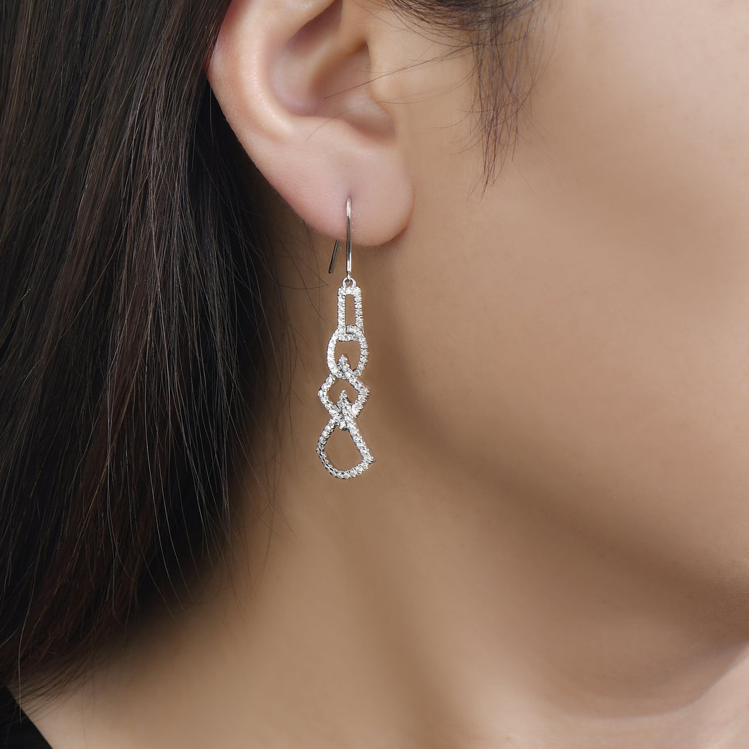 unique jewelry, unique earrings, fashion jewelry, fashion earrings, diamond earrings in white gold, dangling earrings, dangling diamond earrings, drop earrings, diamond drop earrings, dangling drop earring with a design of geometric shapes intertwined with each other. Earrings have a fishhook back. Earrings on model.