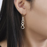 Load image into Gallery viewer, unique jewelry, unique earrings, fashion jewelry, fashion earrings, diamond earrings in yellow gold, dangling earrings, dangling diamond earrings, drop earrings, diamond drop earrings, dangling drop earring with a design of geometric shapes intertwined with each other. Earrings have a fishhook back. on model