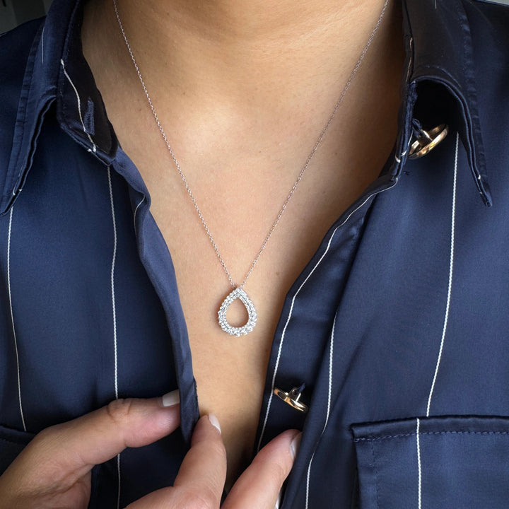 a white gold teardrop-shaped pendant necklace with a halo setting.