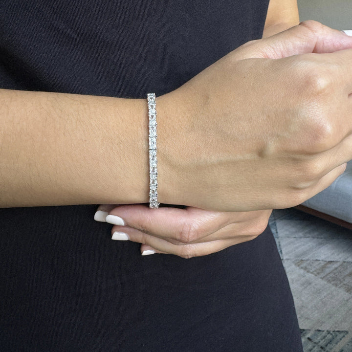 an emerald diamond tennis bracelet in white gold set in an east-west setting worn on a wrist