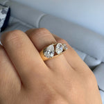 yellow gold three stone ring featuring a pear shaped diamond, an oval shaped diamond, and an asscher cut diamond worn on a hand showing a side view of the ring