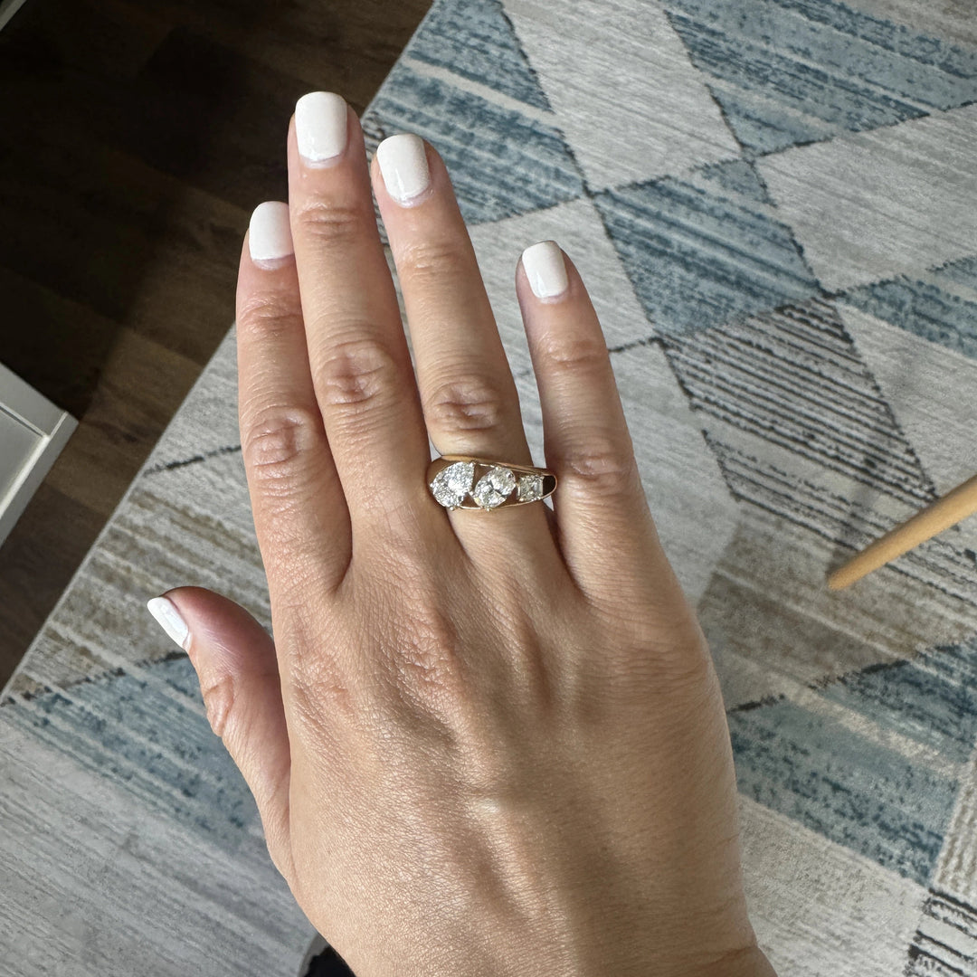 a three stone gold ring with a pear cut diamond, oval cut diamond, and Asscher cut diamond in descending size order.
