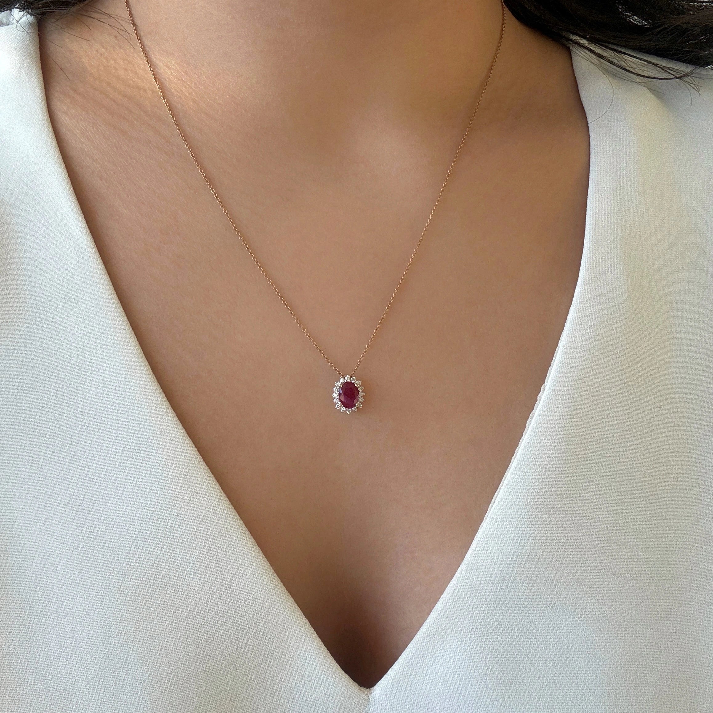 oval ruby pendant with a diamond halo in 14k yellow gold