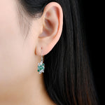 Load image into Gallery viewer, Pear Shape Emerald and White Zircon Dangle Earrings in Sterling Silver on model
