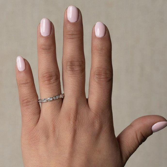 white gold diamond band ring with sideways baguette diamonds set between two prongs going half way eternity worn on a womens hand