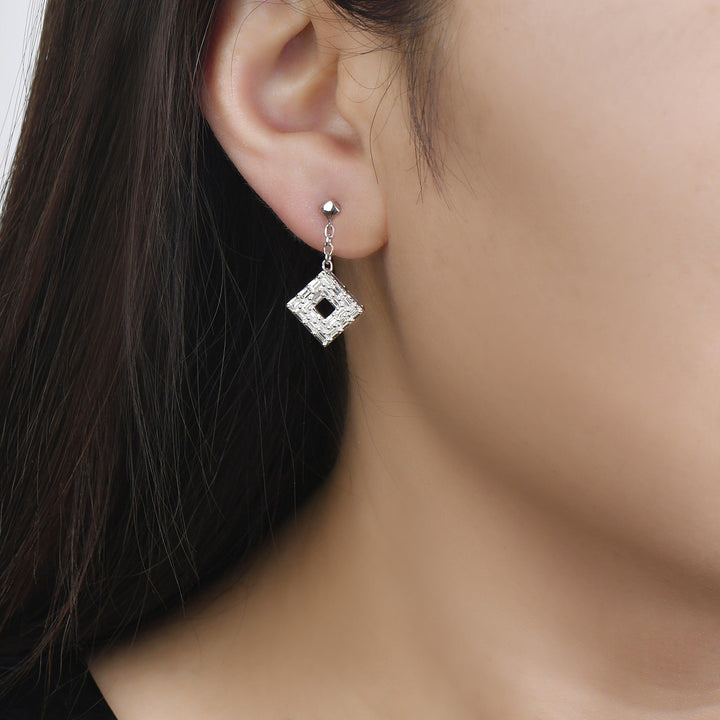 white gold baguette diamond dangle earrings worn on an woman