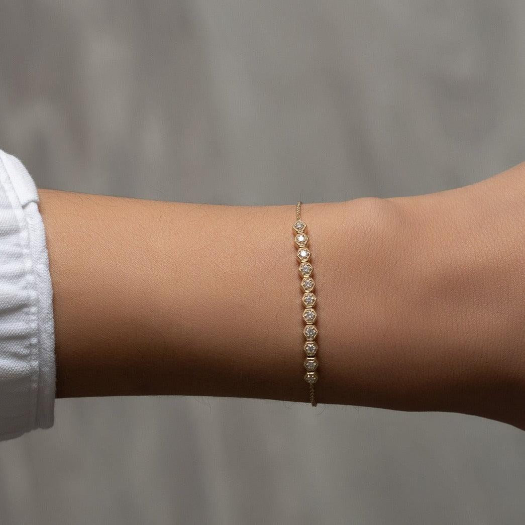 Yellow Gold chain bracelet with a bar of diamonds in a hexagonal setting worn on a wrist
