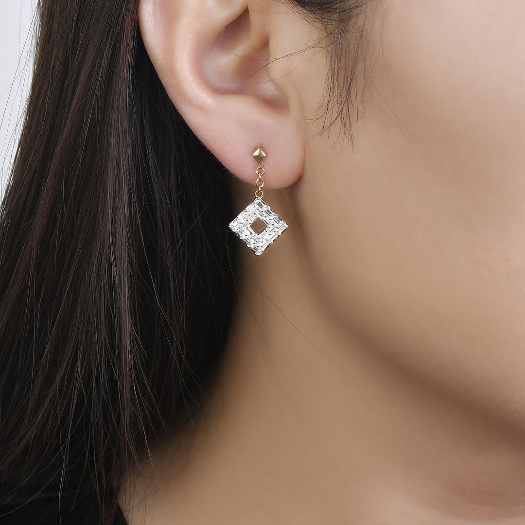yellow gold baguette diamond dangle earrings worn on an woman