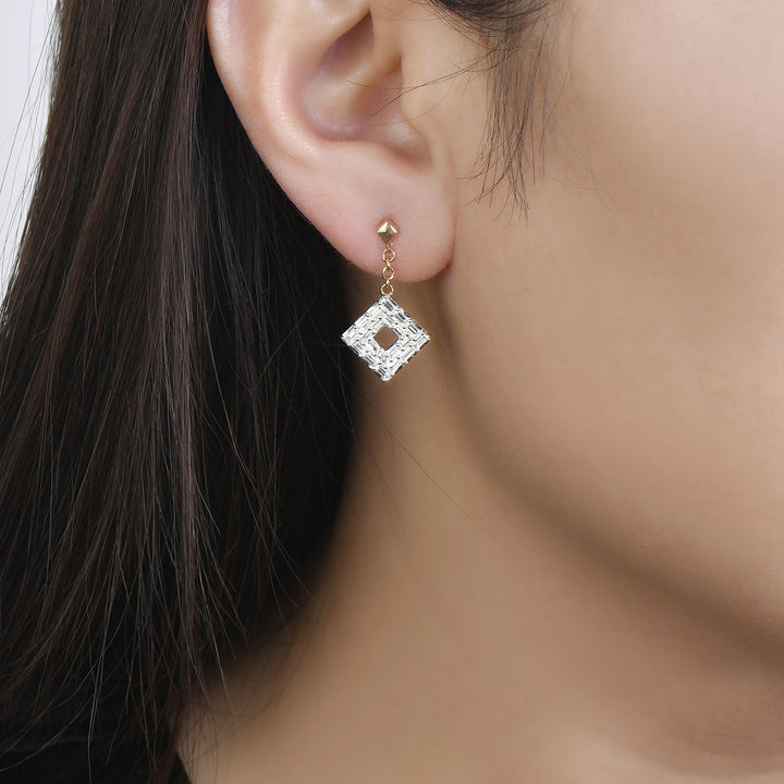 yellow gold baguette diamond dangle earrings worn on an woman