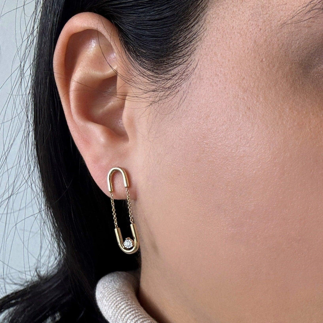 yellow gold chain paperclip earrings with a diamond worn on an ear 