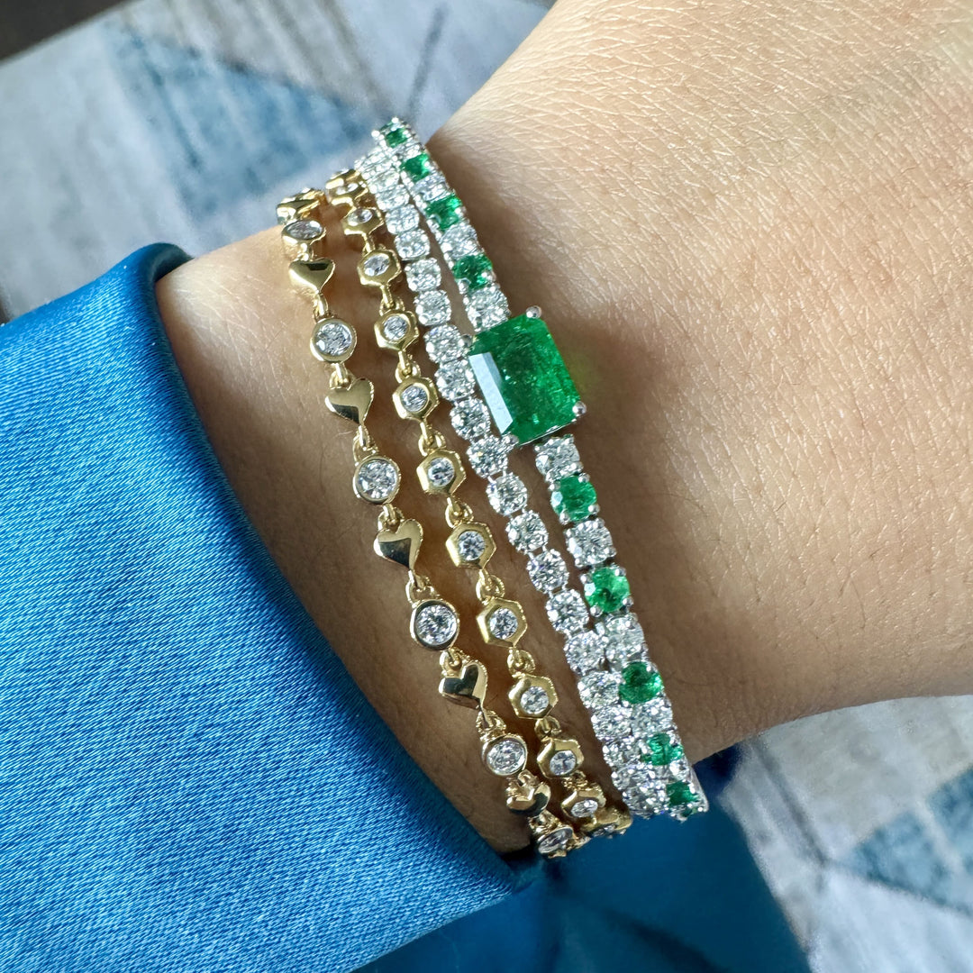 stackable bracelets with emerald and diamond bracelet, diamond tennis bracelet, diamond bezel bracelet in honeycomb bezel, and heart and diamond bracelet in white gold and yellow gold