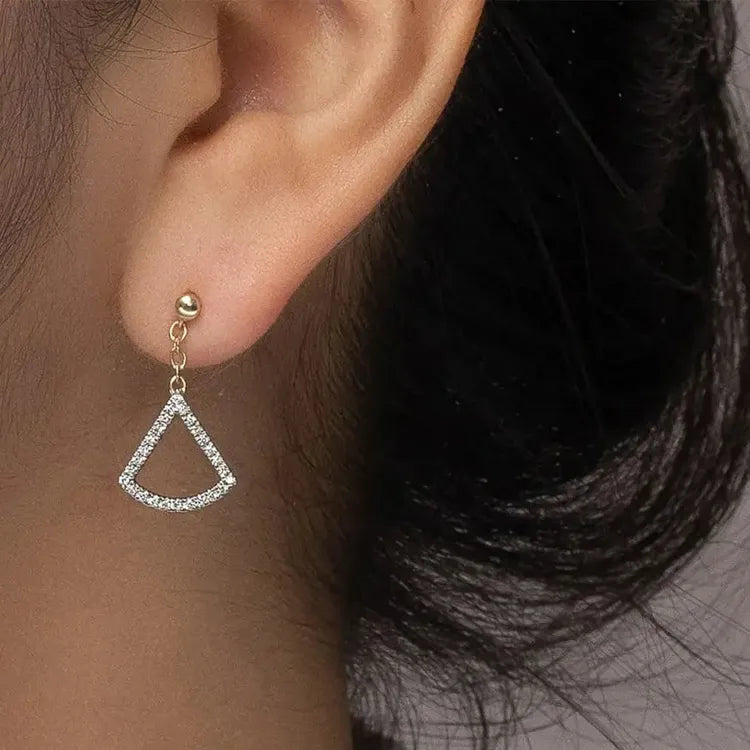Model wearing fan shaped diamond earring in yellow gold. Dangling diamond earring. Diamond fashion earring.