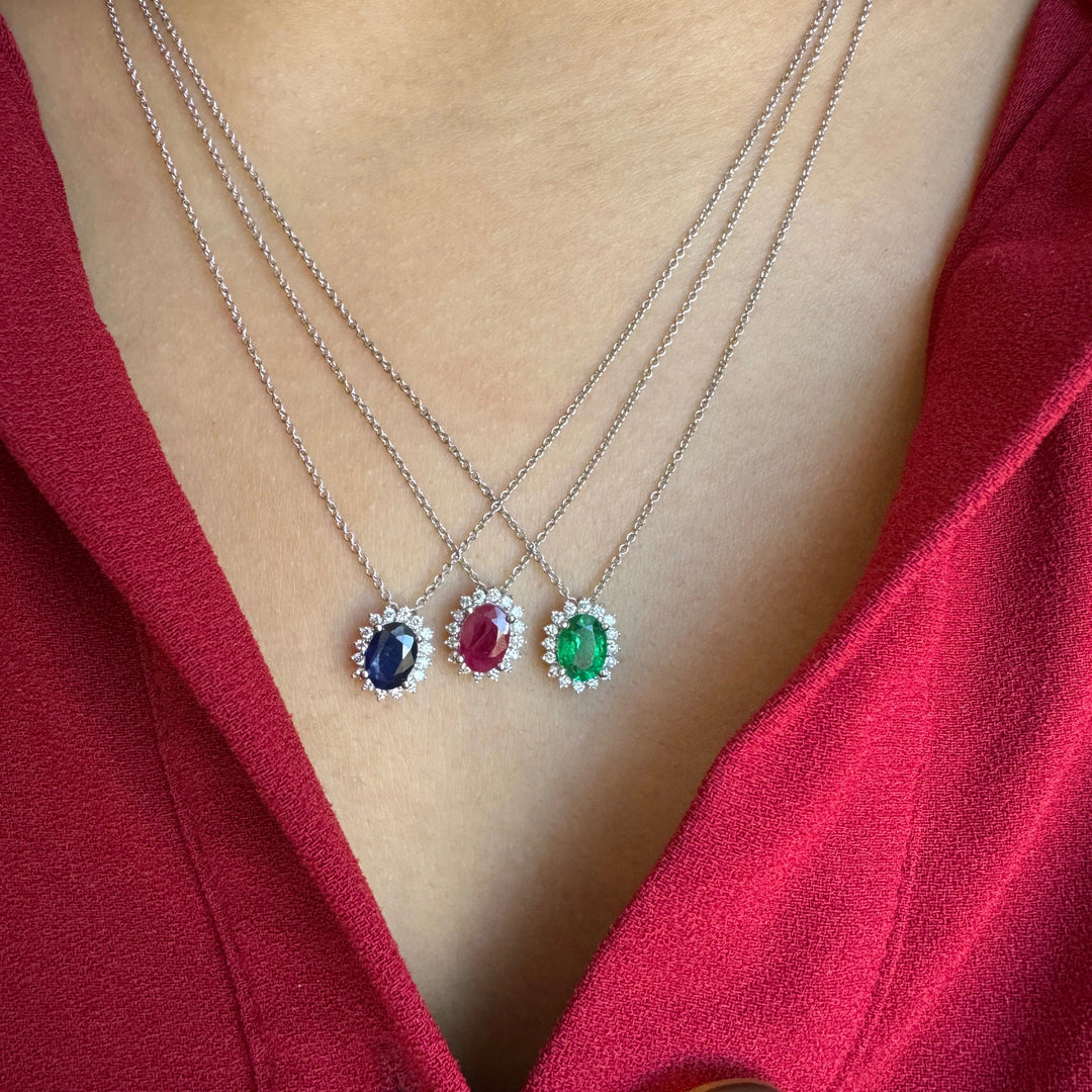 oval shaped sapphire, ruby, and emerald necklaces with diamond halos worn together in white gold