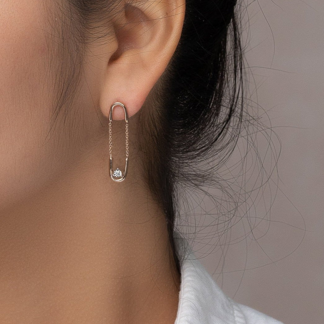 unique jewelry, unique earrings, hanging earrings, dangling earrings, single diamond in the middle of each earring, rose gold dangling diamond earrings, hanging earrings with chain links, paperclip earrings, safety pin earrings. Earrings on model.