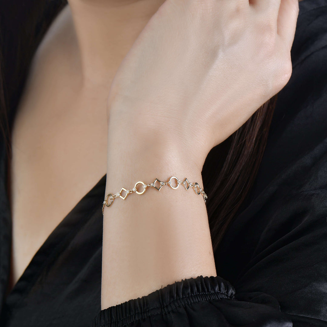14k yellow gold bracelet with diamonds in bezel in alternating circle and diamond motifs on model
